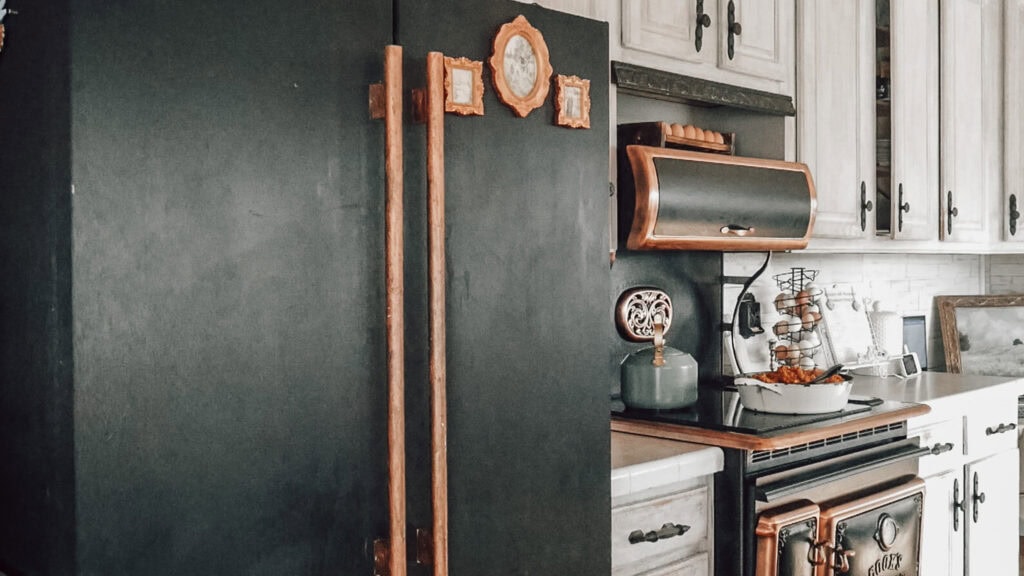 Vintage kitchen with black chalkboard wall and rustic cabinets.